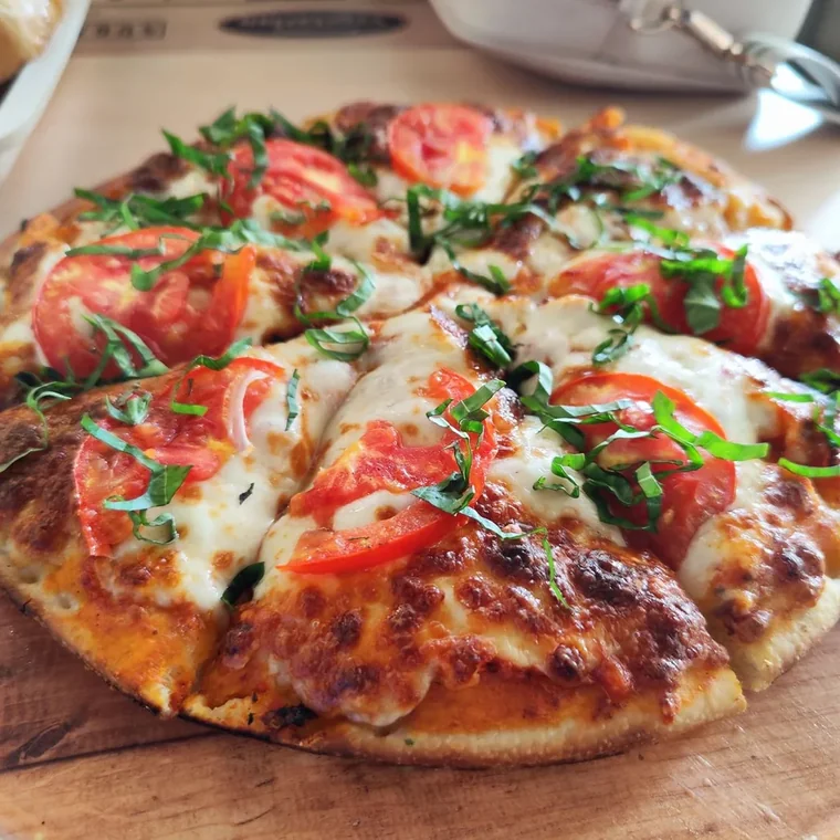Wood-fired Margherita pizza with tomato, mozzarella and fresh basil on a round wooden board